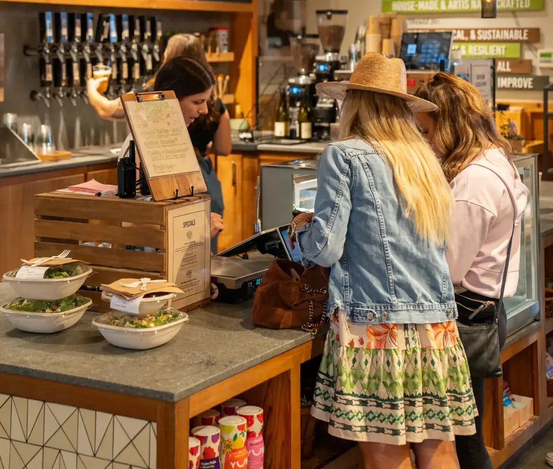Customers shopping for fresh food and local products at a neighborhood market.