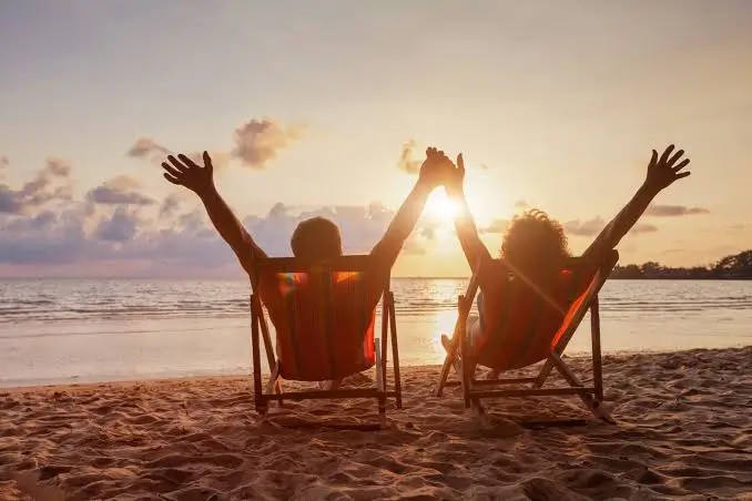 Couple relaxing on the beach at sunset.