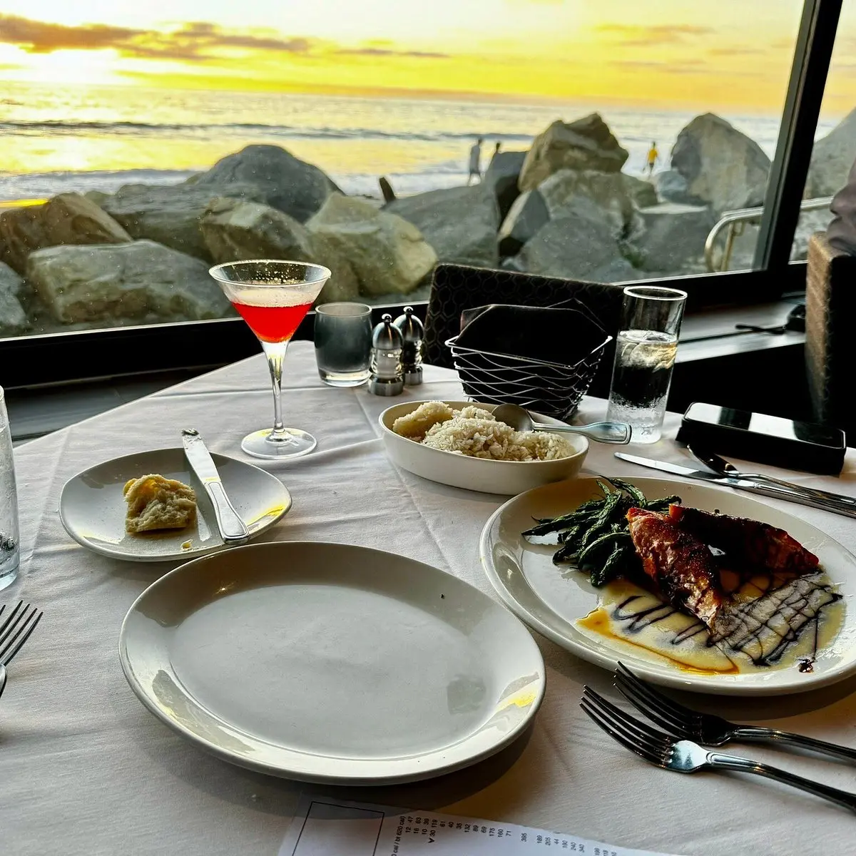 Dining table with a cocktail and ocean view.